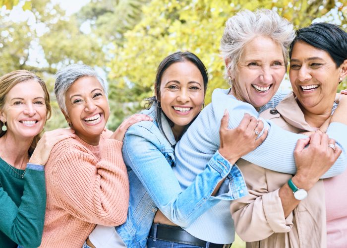 Friends, park and group of women hug enjoying bonding, quality time and relax in nature together. Diversity, friendship and portrait of happy senior females with smile, embrace and peace outdoors